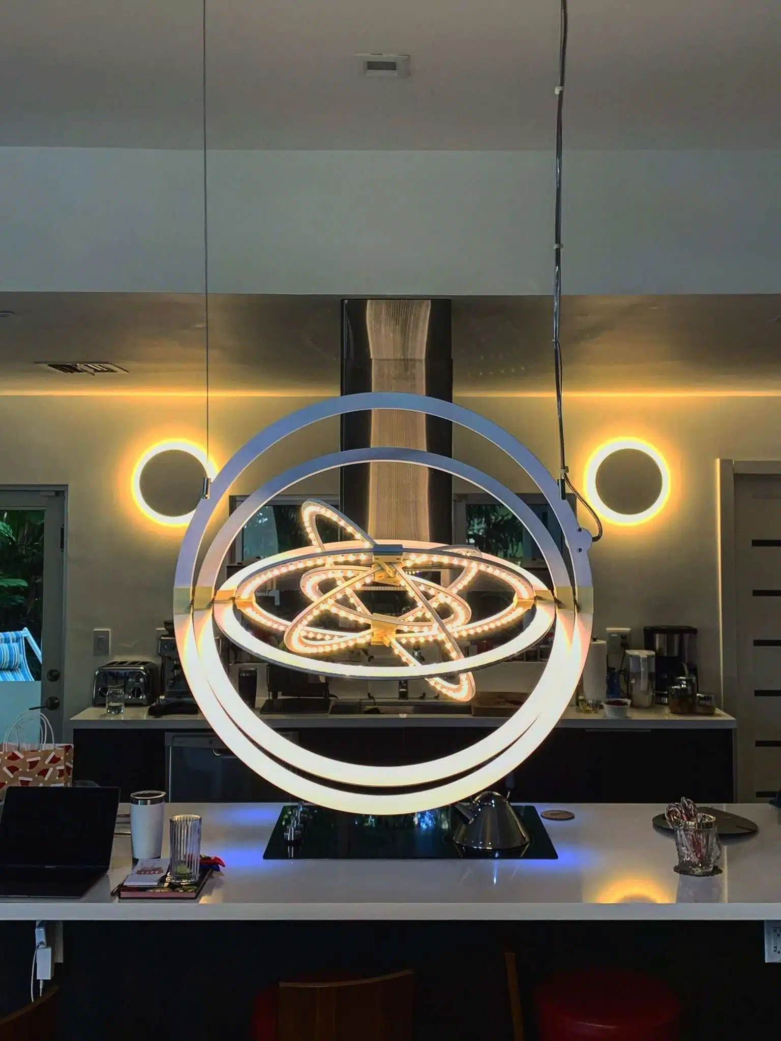 Spherical brass pendant light fixture installed above a residential nook near bay windows – customized home lighting design.