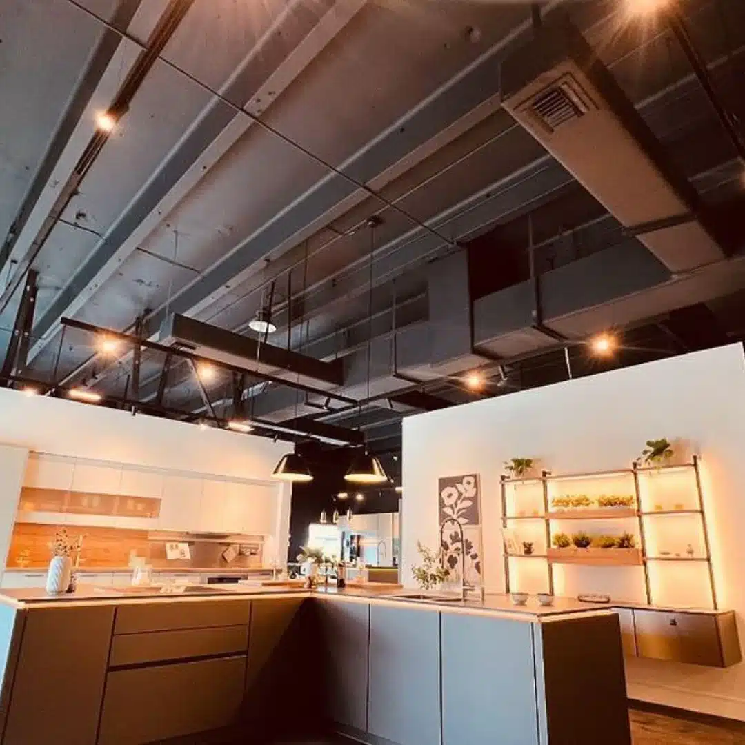 Modern kitchen showroom with custom lighting and exposed ceiling conduit installed by Xmart Power Electric.