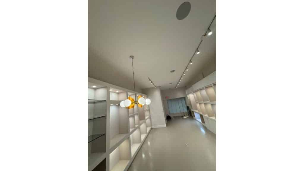 Commercial showroom interior with custom built-in shelving, track lighting, and modern globe pendant light.