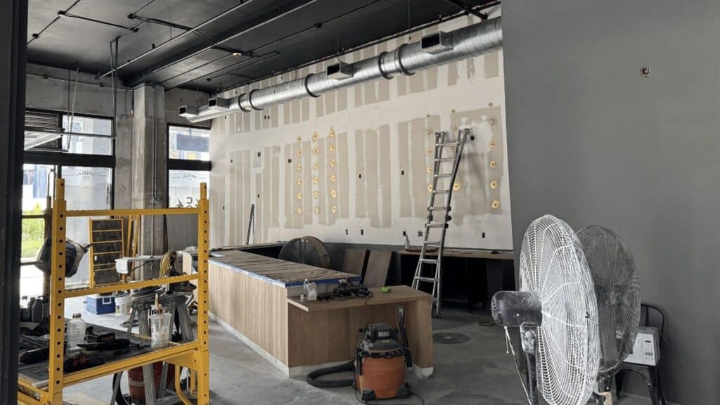 Modern commercial interior under construction with exposed ductwork and wooden counter.