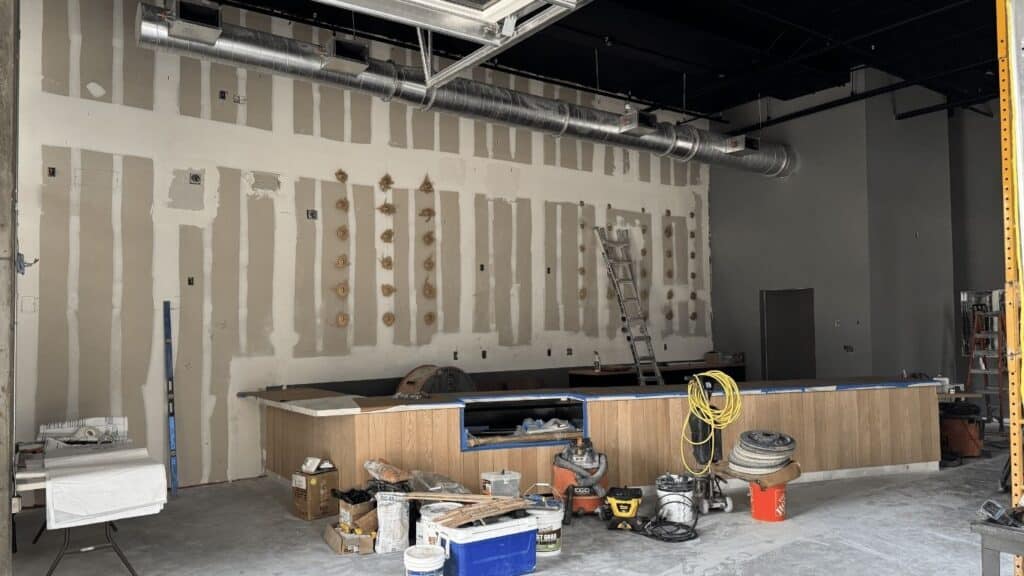 Commercial interior build-out with exposed ductwork and unfinished drywall.