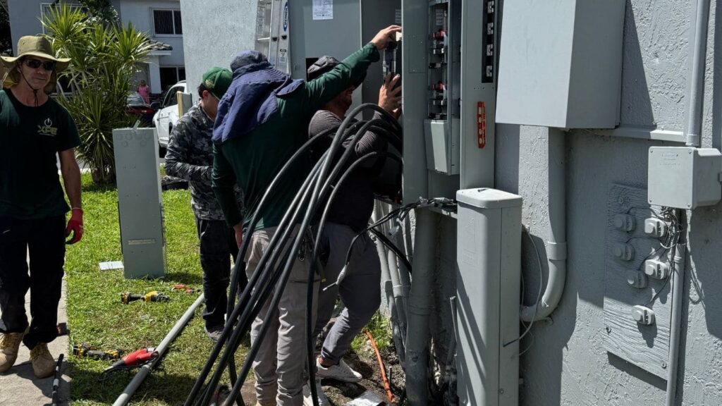 Professional electricians performing a main electrical panel upgrade and feeder wire installation for a residential building.