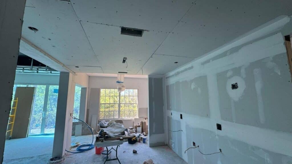 Interior room under renovation with newly installed drywall on walls and ceiling.
