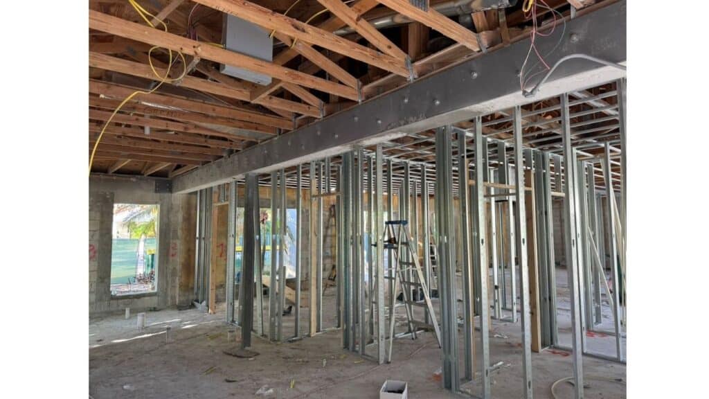 Internal view of commercial steel stud framing with exposed wooden roof trusses and electrical wiring.