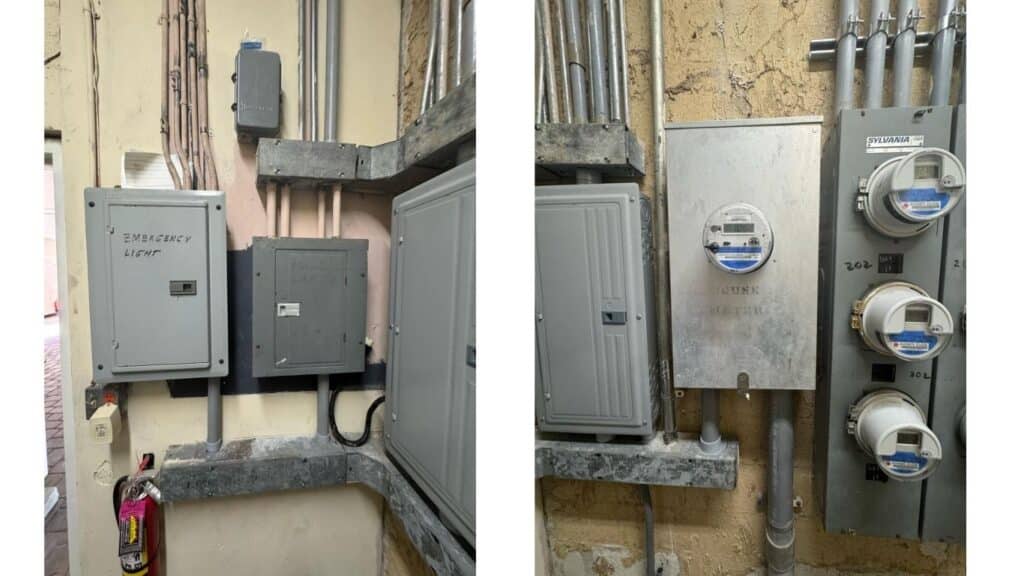 Commercial electrical service entrance with emergency light panel, house meter, and Sylvania meter bank.