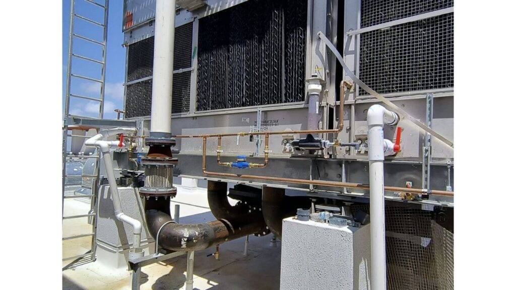 Industrial cooling tower installation with large diameter PVC piping, copper lines, and professional structural supports.