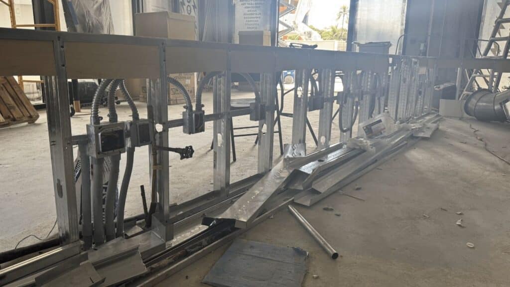 Commercial electrical rough-in for a kitchen island or service counter with metal stud framing and armored cable (BX) wiring.