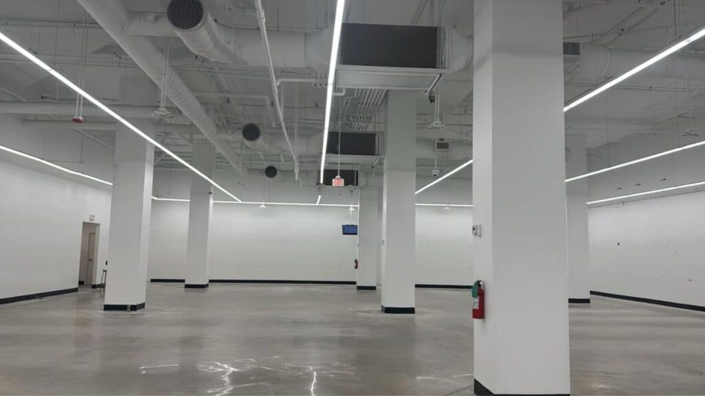 Modern commercial interior with continuous LED linear lighting, exposed HVAC ductwork, and polished concrete floors.