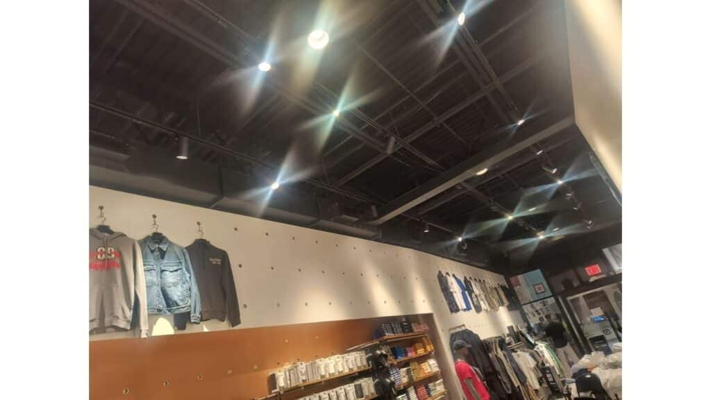 Modern retail store with industrial black ceilings, professional track lighting, and recessed spotlights for apparel display.