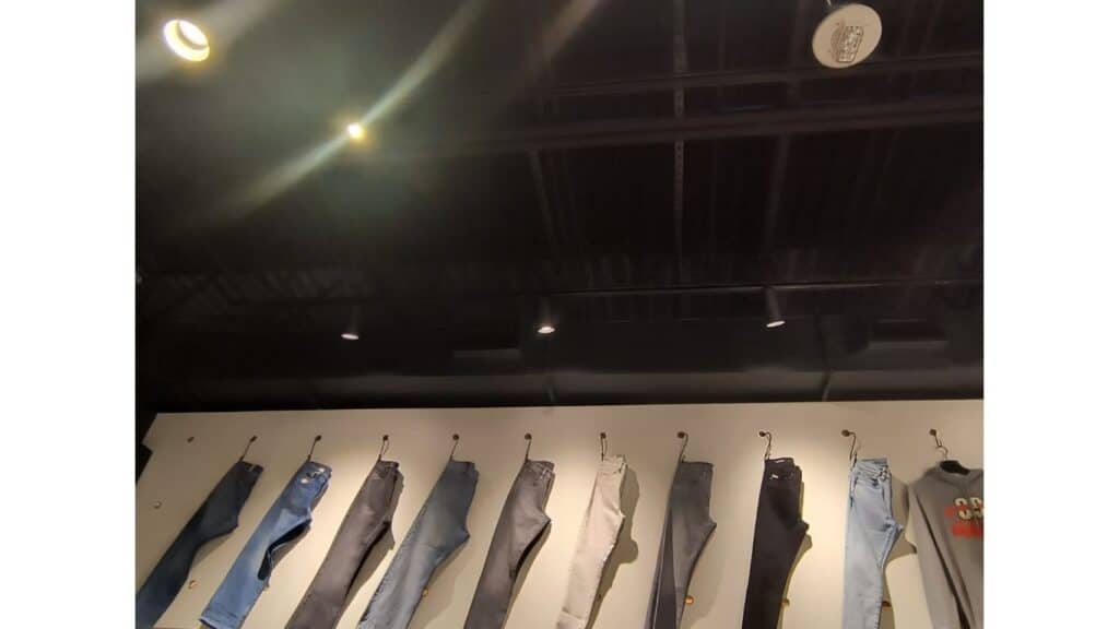 Retail apparel display with professional LED track lighting and focused spotlights for clothing highlights.