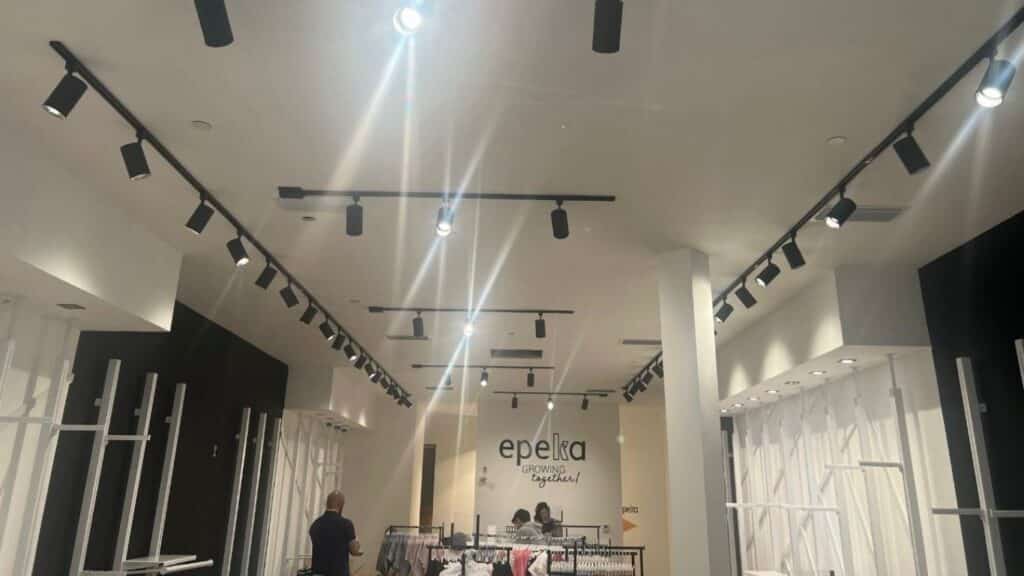 Modern retail store interior featuring professional black track lighting systems and recessed ceiling spotlights.