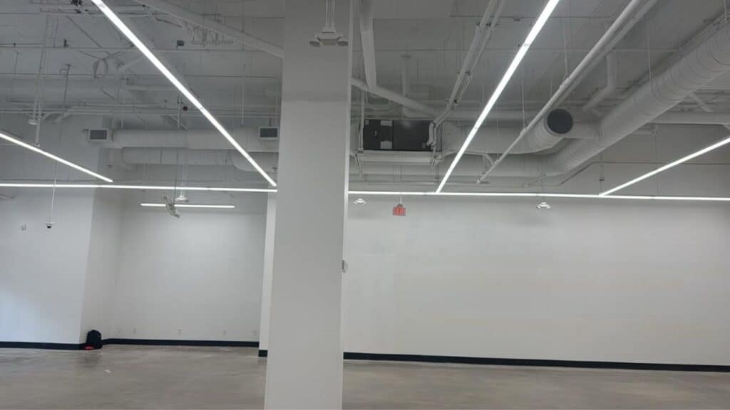 Large open-concept commercial space featuring modern LED linear lighting and exposed HVAC ductwork.
