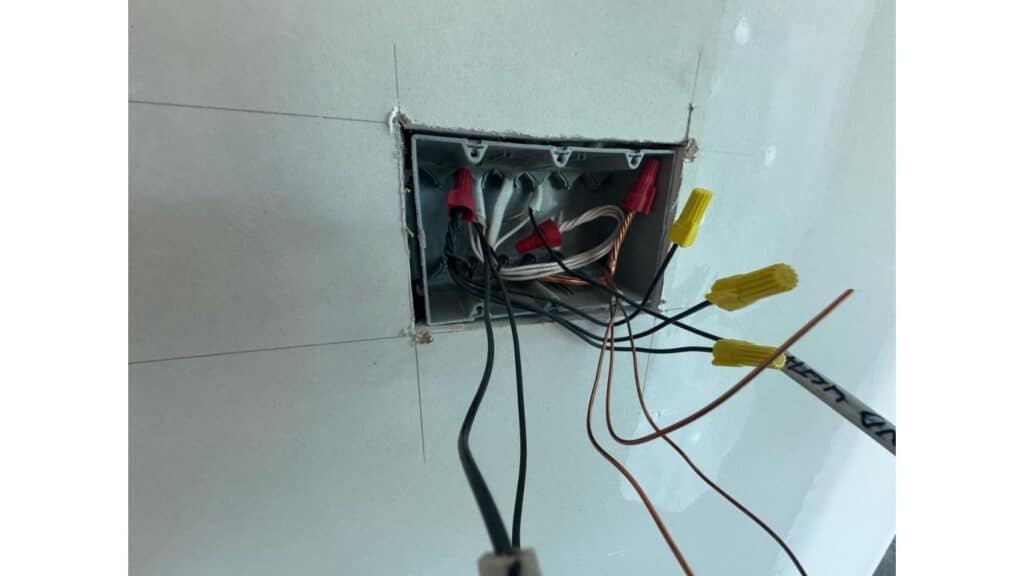 Interior view of a multi-gang electrical junction box with organized wiring and color-coded wire nut connectors.